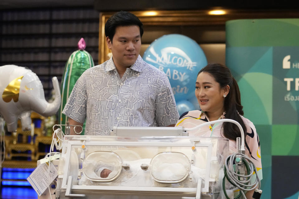 Paetongtarn Shinawatra, right, a leading Thai politician and youngest daughter of exiled former deposed Thai leader Thaksin Shinawatra, stands behind an incubator with her new born son, along with, left, her husband Pidok Sooksawas during press conference in Bangkok, Thailand, Wednesday, May 3, 2023. The frontrunning candidate for prime minister of Thailand said Wednesday she’s eager to get back on the campaign trail, just two days after giving birth. (AP Photo/Sakchai Lalit)