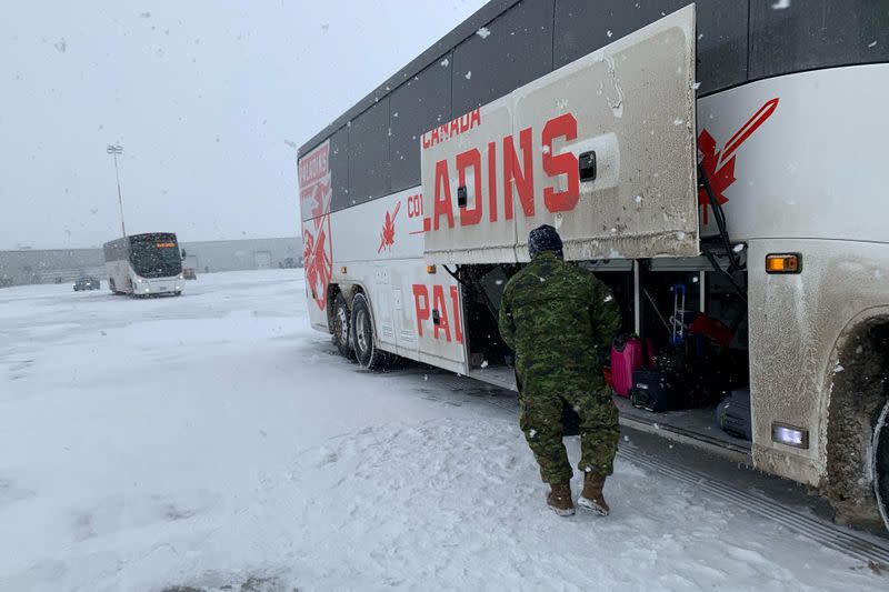 Canadian Forces personnel load luggage onto a bus for Canadians who had been evacuated from China as they disembark from another aircraft at Canadian Forces Base (CFB) Trenton in Trenton