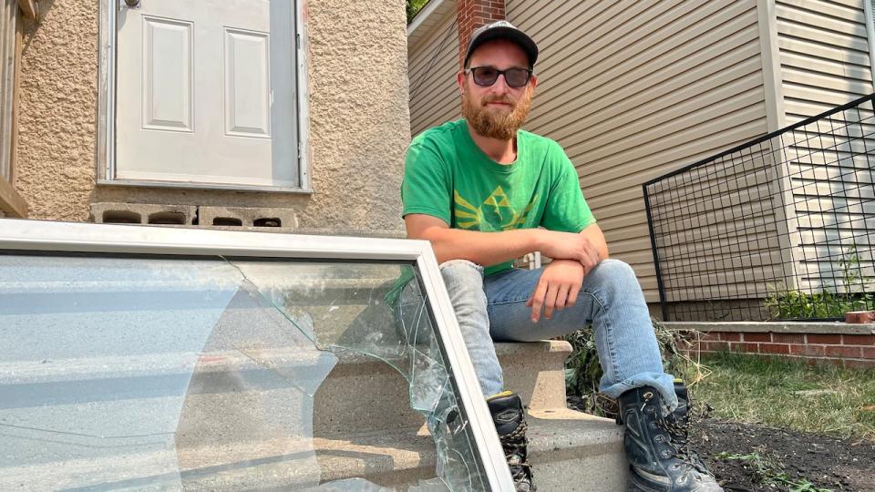 Kyle Klochko poses with the broken window on Thursday, sitting in front of the door since cleaned of the red handprints.