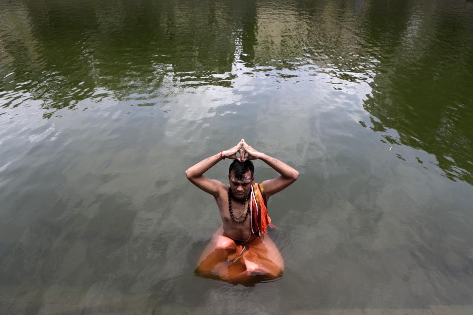 A Hindu devotee sits in a pond and performs rituals during solar eclipse at Banganga in Mumbai, India, Sunday, June 21, 2020.(AP Photo/Rajanish Kakade)