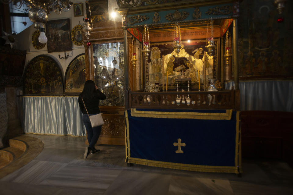 Christian worshiper prays in the Church of the Nativity, traditionally believed to be the birthplace of Jesus Christ, in the West Bank city of Bethlehem, Monday, Nov. 23, 2020. Normally packed with tourists from around the world at this time of year, Bethlehem resembles a ghost town – with hotels, restaurants and souvenir shops shuttered by the pandemic. (AP Photo/Majdi Mohammed)