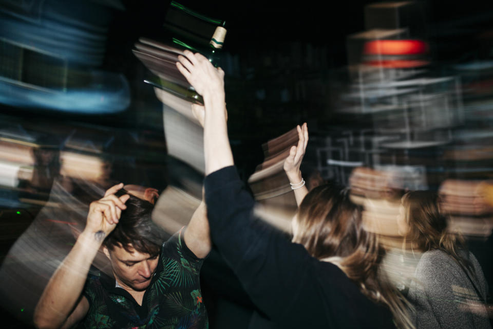 Image of blurred figures dancing in a low-light club setting