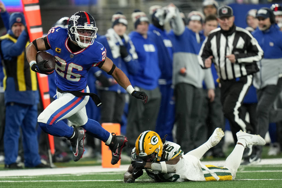 New York Giants running back Saquon Barkley (26) avoids a tackle by Green Bay Packers safety Darnell Savage (26) during the fourth quarter of an NFL football game, Monday, Dec. 11, 2023, in East Rutherford, N.J. (AP Photo/Seth Wenig)