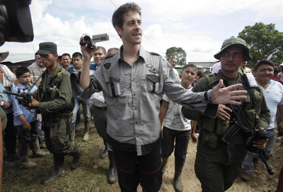 French journalist Romeo Langlois, center, is escorted by rebels of the Revolutionary Armed Forces of Colombia, FARC, upon their arrival to San Isidro, southern Colombia, Wednesday, May 30, 2012. Langlois , who was taken by rebels on April 28 when they attacked troops he was accompanying on a cocaine-lab eradication mission, was handed over by the rebels to a delegation that included a French diplomat in San Isidro. (AP Photo/Fernando Vergara)