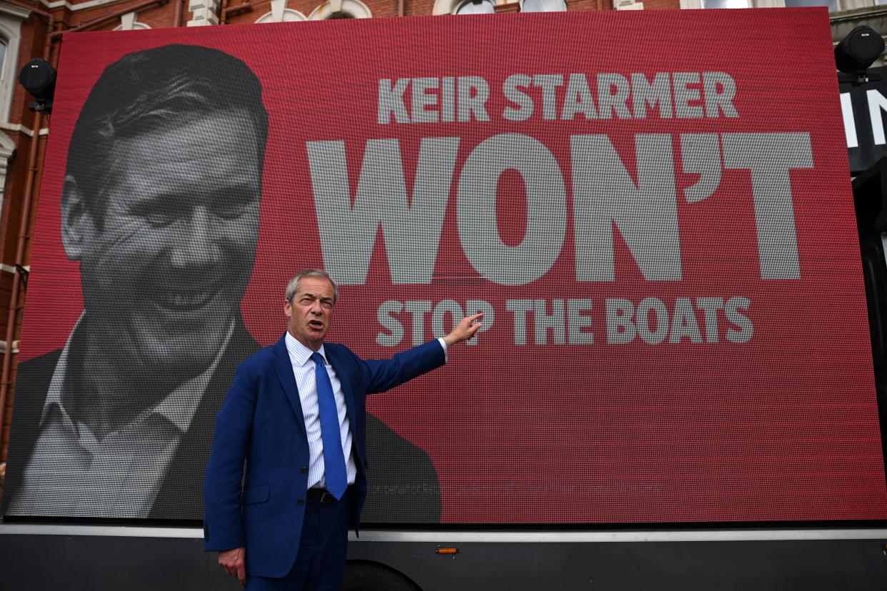 Leader of Reform UK Nigel Farage stands in front of a van reading 