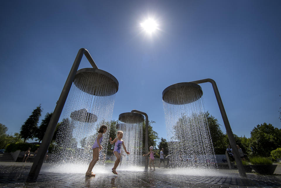 Children cool off in a public fountain in Vilnius, Lithuania, Saturday, June 19, 2021. The heat wave continues in Lithuania as temperature rose to as high as 32 degrees Celsius (89.6 degrees Fahrenheit). (AP Photo/Mindaugas Kulbis)
