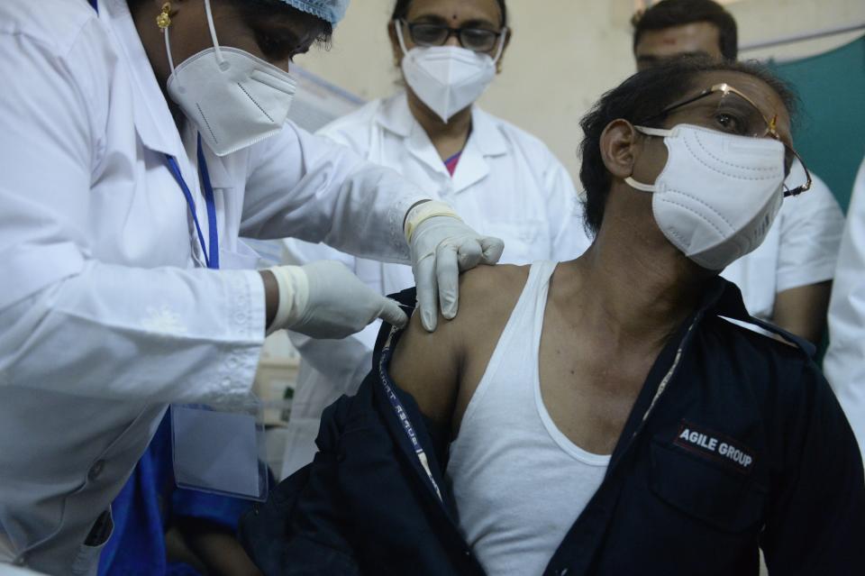 A medical worker inoculates a security guard with a Covid-19 coronavirus vaccine at the King Koti hospital in Hyderabad on January 16, 2021. (Photo by Noah SEELAM / AFP) (Photo by NOAH SEELAM/AFP via Getty Images)