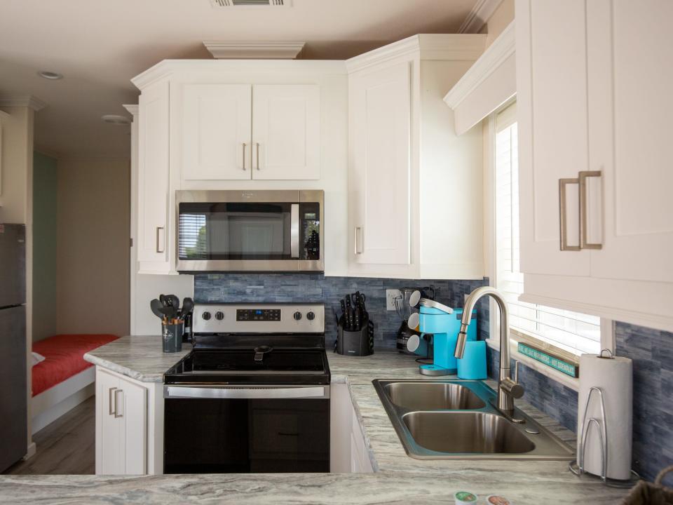 A kitchen with cabinets, sink, microwave, stove, oven.