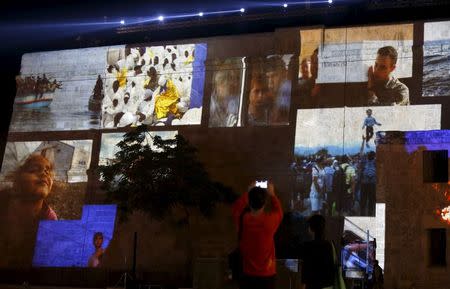 People take pictures of projections showing images of migrants on the facade of St James Cavalier during a rehearsal of the opening ceremony of the 2015 Valletta Summit on Migration in Valletta, Malta, November 10, 2015. REUTERS/Darrin Zammit Lupi