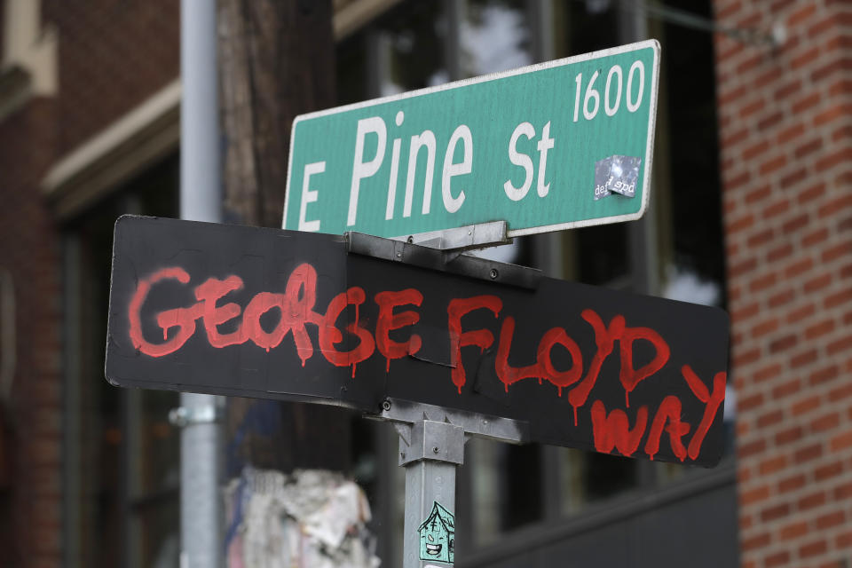 A street sign at the intersection of 11th Ave. and Pine St. has been changed to read "George Floyd Way," Wednesday, June 24, 2020, inside the CHOP (Capitol Hill Occupied Protest) zone in Seattle. The area has been occupied since a police station was largely abandoned after clashes with protesters, but Seattle Mayor Jenny Durkan said Monday that the city would move to wind down the protest zone following several nearby shootings and other incidents that have distracted from changes sought by peaceful protesters opposing racial inequity and police brutality. (AP Photo/Ted S. Warren)