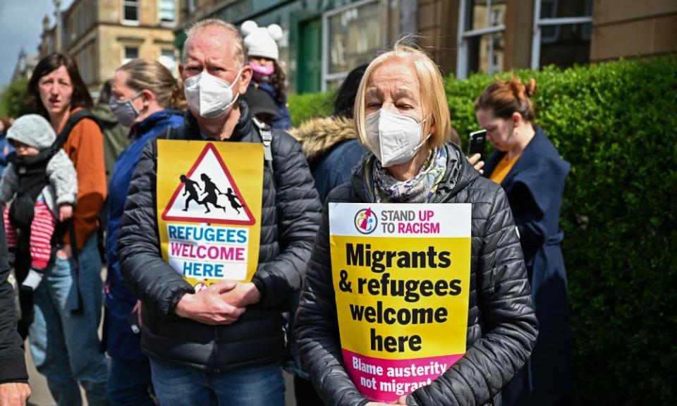 Protesters hold up placards as they block a immigration enforcement van, stopping it from leaving Kenmure Street in Glasgow.