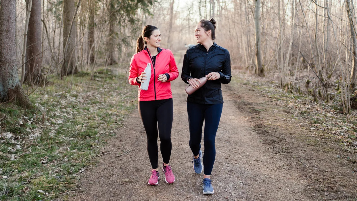 Two women doing walking workout in forest.