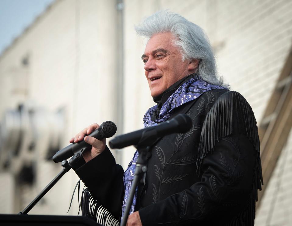 Country music star Marty Stuart introduces Dolly Parton before unveiling of a mural, inspired by her song "Wildflowers" in Philadelphia, Miss., Saturday, Aug. 26, 2023.