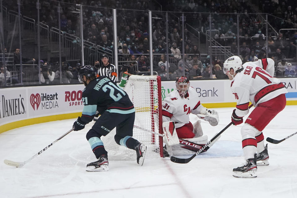 Carolina Hurricanes goaltender Frederik Andersen (31) and defenseman Brady Skjei, right, watch as Seattle Kraken center Alex Wennberg (21) passes the puck behind the net during the first period of an NHL hockey game Wednesday, Nov. 24, 2021, in Seattle. (AP Photo/Ted S. Warren)