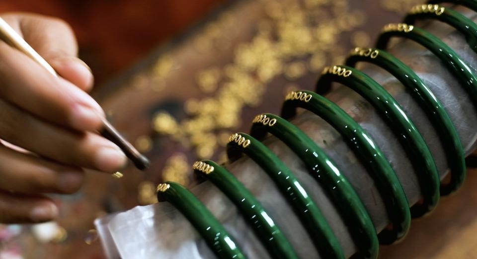 An artisan decorates glass bangles