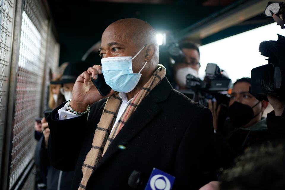 New York City Mayor Eric Adams calls the police while keeping his eye on a fight in the street while waiting for the subway to City Hall in New York, Saturday, Jan. 1, 2022.