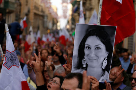 A demonstrator carries a photo of assassinated anti-corruption journalist Daphne Caruana Galizia as others sing the national anthem at the end of a protest against government corruption revealed by the Daphne Project, in Valletta, Malta April 29, 2018. REUTERS/Darrin Zammit Lupi