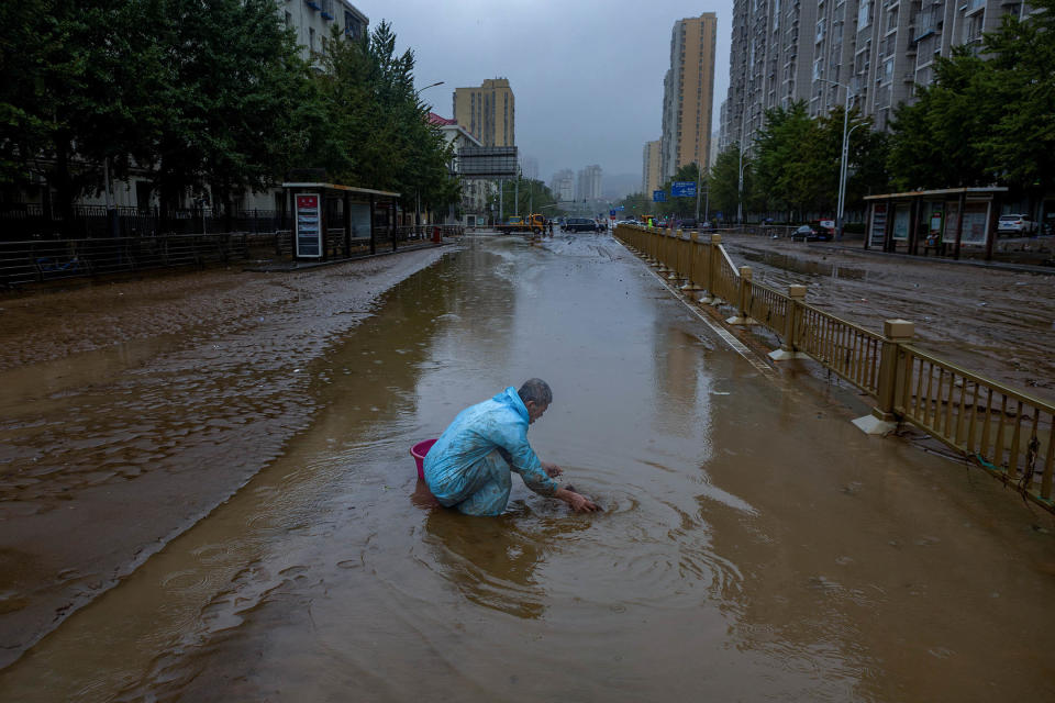 2023年8月1日，北京，一名男子在一條被洪水淹沒的街道上。攝：Thomas Peter/Reuters/達志影像