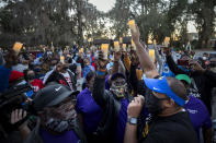 FILE - In this Feb. 23, 2021, file photo, Ahmaud Arbery's father, Marcus Arbery, bottom center, listens to Jason Vaughn speak during a memorial walk and candlelight vigil for Ahmaud at the Satilla Shores development in Brunswick, Ga. Arbery's son was shot and killed while running in a neighborhood outside the port city. Jury selection in the case is scheduled to begin Monday, Oct. 18. (AP Photo/Stephen B. Morton, File)