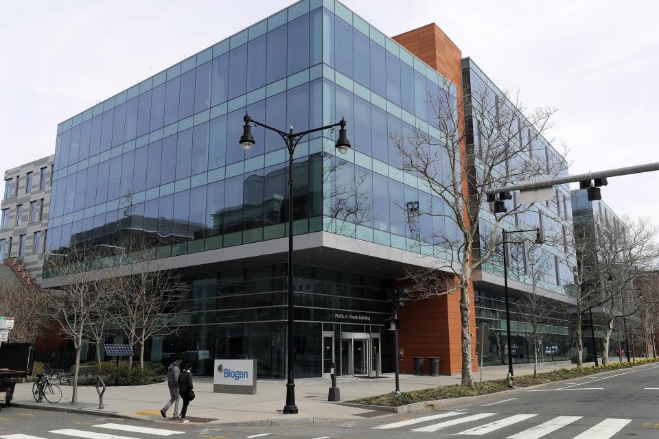 People walk past the Biogen Inc., headquarters, Wednesday, March 11, 2020, in Cambridge, Mass. Seventy of Massachusetts' first 92 confirmed coronavirus cases have been linked to a meeting of Biogen executives that was held at the Marriott Long Wharf hotel in Boston in late February 2020. For most people, the virus causes only mild or moderate symptoms, such as fever and cough. For some, especially older adults and people with existing health problems, it can cause more severe illness, including pneumonia. The vast majority of people recover from the new virus. (AP Photo/Steven Senne)