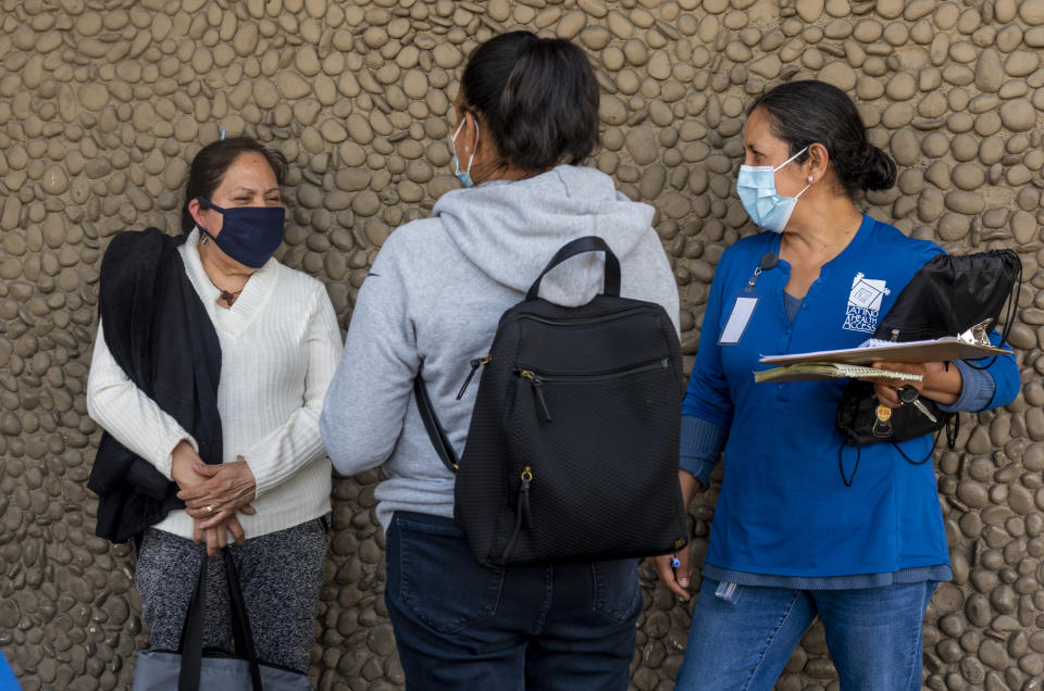 Una promotora de la salud (derecha) promueve la vacunación contra el covid-19 en la comunidad latina en una mediante una unidad móvil ubicada en el estacionamiento de un supermercado en Santa Ana, California. (Getty Images)