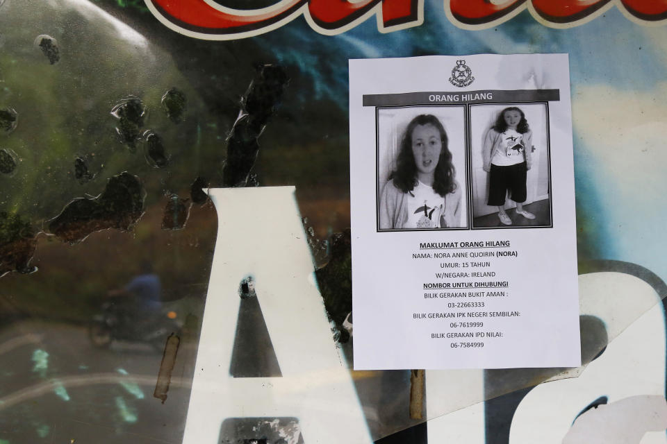 A poster of a missing British girl Nora Anne Quoirin is seen as a motorcyclist, reflected on a acrylic, rides past in Seremban, Negeri Sembilan, Malaysia, Saturday, Aug. 10, 2019. The parents of the 15-year-old London girl who mysteriously disappeared from a Malaysian resort a week ago said Saturday that she wasn't independent and had difficulty walking, in new details to support their conviction that she was abducted. (AP Photo/Lai Seng Sin)