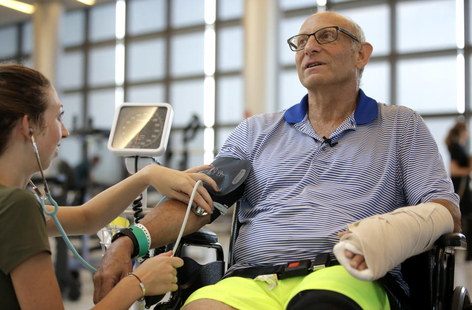 FILE - In this Aug. 28, 2018 file photo, shark attack victim William Lytton, of Scarsdale, N.Y. has his vital signs checked by physical therapist Caitlin Geary at Boston's Spaulding Rehabilitation Hospital. Lytton suffered deep puncture wounds to his leg and torso after being attacked by a shark on Aug. 15, 2018 while swimming off a beach in Truro, Mass. A prominent shark researcher says smaller, younger great white sharks are being spotted in greater numbers off Cape Cod. (AP Photo/Steven Senne, File)