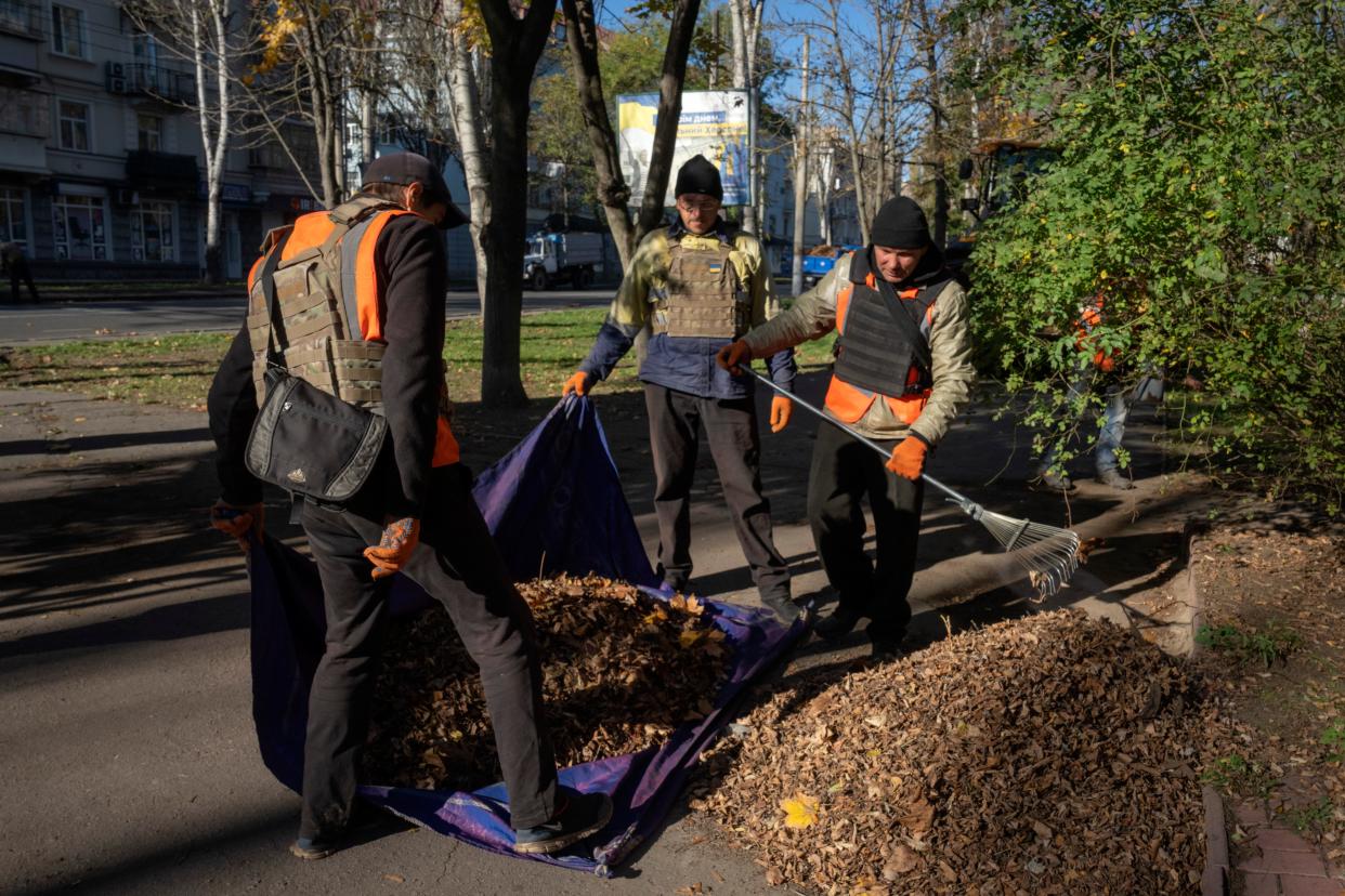 Municipal workers wearing protective vests clear autumn leaves from the streets in Kherson, Ukraine (Copyright 2023 The Associated Press. All rights reserved.)