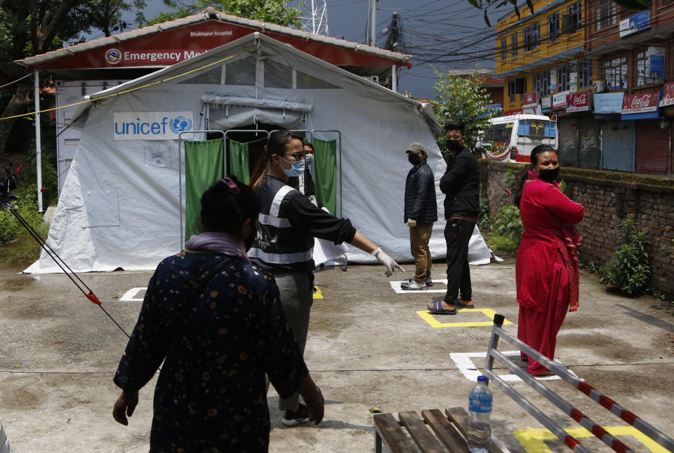 Punam Karmacharya, del grupo de manejo de emergencias RYC-1, da instrucciones a personas que se presentan para hacerse pruebas del coronavirus en un hospital de Bhaktapur, Nepal, el 26 de mayo del 2020. (AP Photo/Niranjan Shrestha)