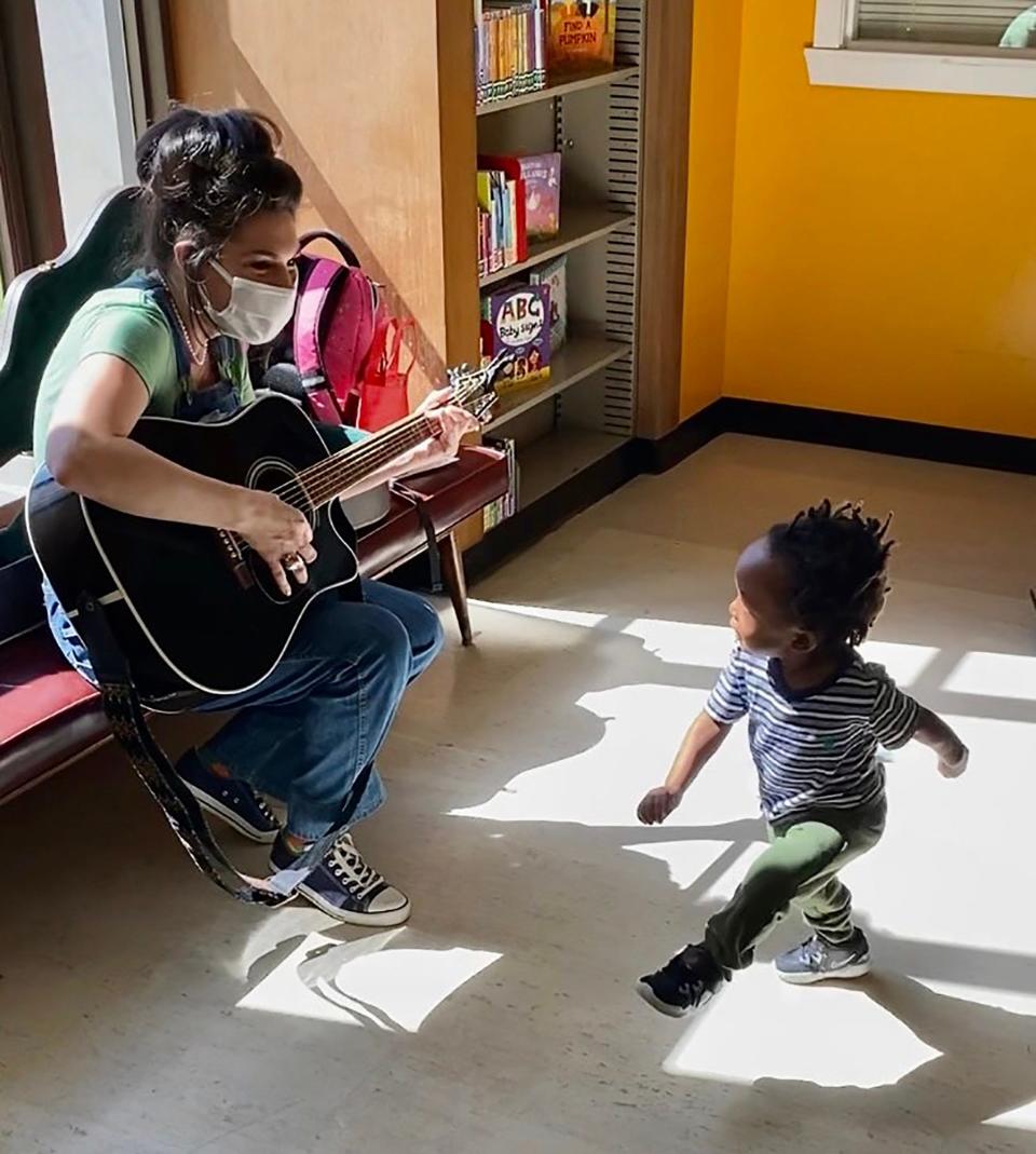 Danielle Carlomusto, 44, of Grosse Pointe Woods plays a song as a child dances dances along during musical story time as part of her Gro-Town event in the children’s library at the main branch of the Detroit Public Library on Woodward Avenue in Detroit on Thursday, April 13, 2023.