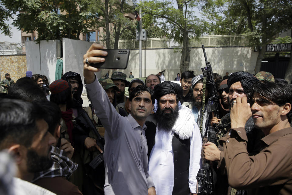An Afghan takes a selfie with Taliban fighters on patrol in Kabul, Afghanistan, Thursday, Aug. 19, 2021. The Taliban celebrated Afghanistan's Independence Day on Thursday by declaring they beat the United States, but challenges to their rule ranging from running a country severely short on cash and bureaucrats to potentially facing an armed opposition began to emerge. (AP Photo/Rahmat Gul)