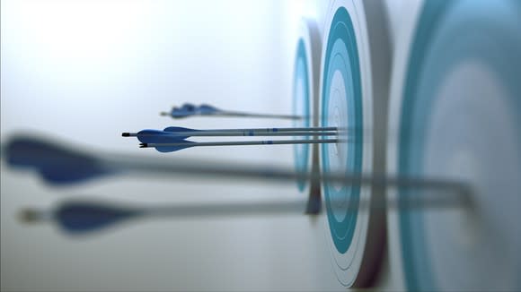 Blue darts hitting bull's-eyes on three blue dartboards.