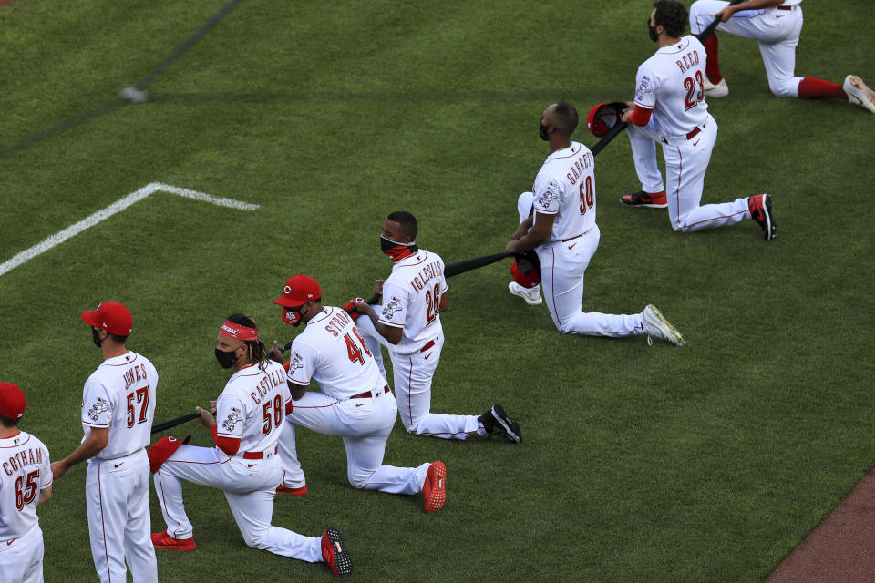 Cincinnati Reds' Luis Castillo (58), Pedro Strop (46), Raisel Iglesias (26), Amir Garrett (50) and Cody Reed (23) take a knee prior to a baseball game against the Detroit Tigers at Great American Ballpark in Cincinnati, Friday, July 24, 2020. (AP Photo/Aaron Doster)