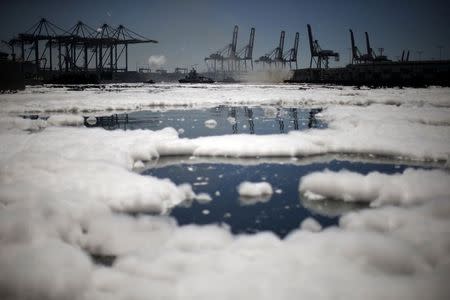 Firefighters douse a smouldering dock fire that broke out on Monday evening and burned about 150 feet (45 meters) of a wharf area at the Port of Los Angeles, as foam swirls around the dock, California September 23, 2014. REUTERS/Lucy Nicholson