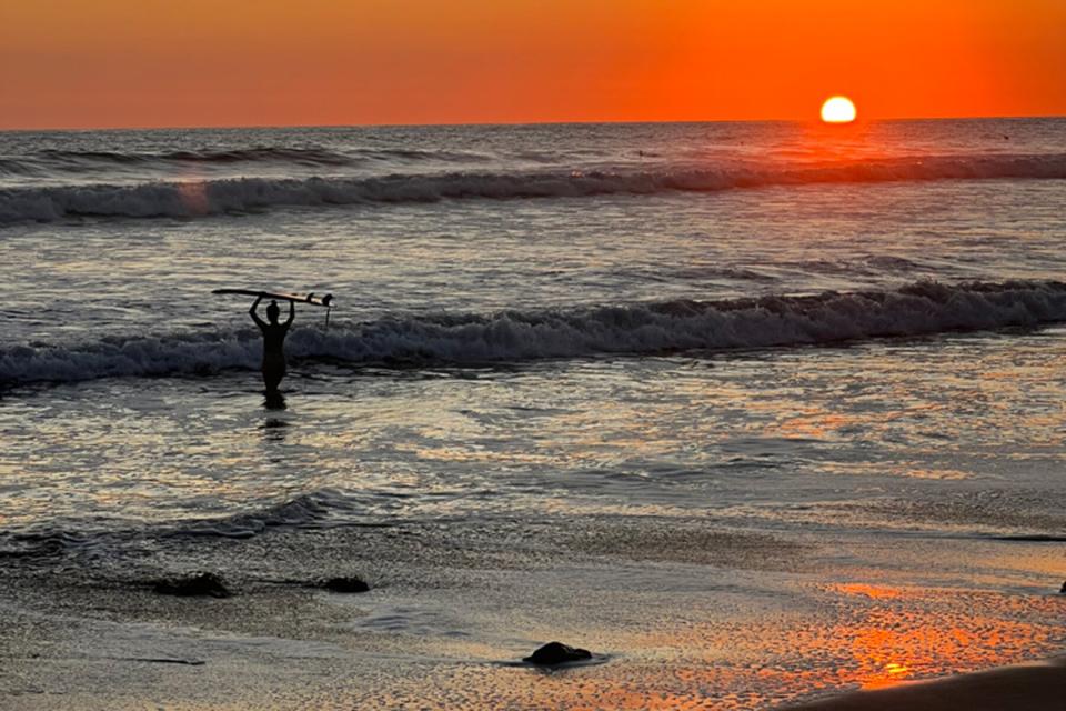A surfer in the water during sunset in Santa Teresa