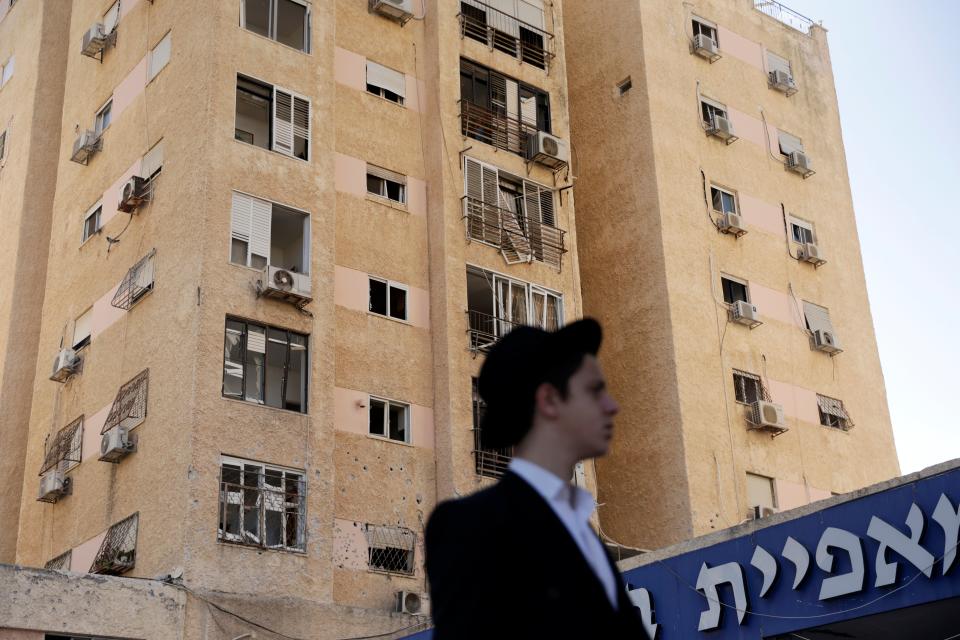 An Israeli man walks in front of a building hit by Hezbollah rocket fire on Tuesday (Getty Images)