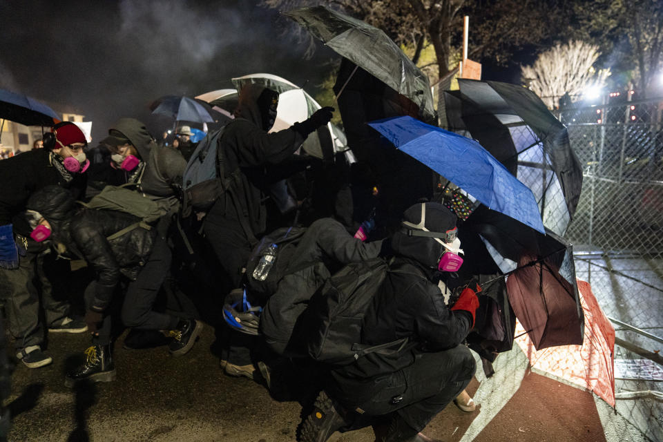 Demonstrators using umbrellas as shields approach a point in a perimeter security fence during a protest over the fatal shooting of Daunte Wright during traffic stop, outside the Brooklyn Center Police Department, Friday, April 16, 2021, in Brooklyn Center, Minn. (AP Photo/John Minchillo)