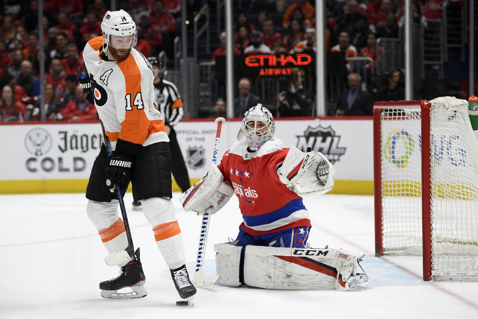 Philadelphia Flyers center Sean Couturier (14) and Washington Capitals goaltender Braden Holtby (70) look for the puck during the first period of an NHL hockey game Wednesday, March 4, 2020, in Washington. (AP Photo/Nick Wass)