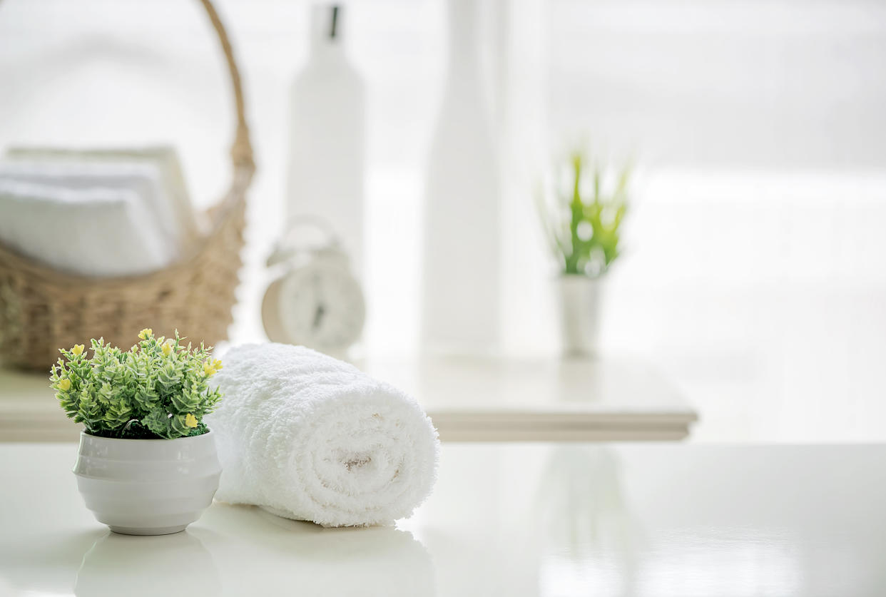 Roll up of white towels on white table with copy space on blurred living room background. For product display montage.