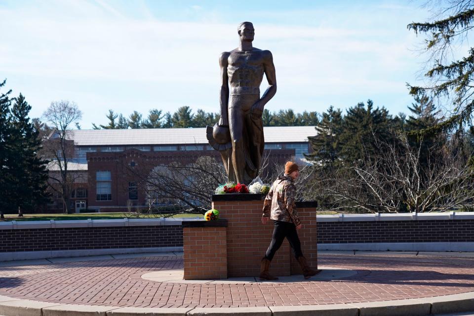 A person leaves flowers at the base of the Sparty statue following an active shooting incident on the Michigan State University campus in East Lansing on Tuesday, February 14, 2023, that left three people dead and multiple injured.