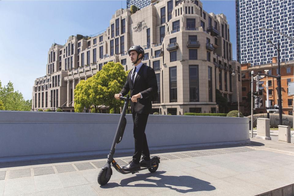 A man wearing a business suit while riding a Segway Scooter through a city