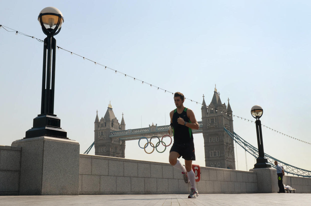 Un joggeur passant devant les anneaux olympiques suspendus sur Tower Bridge, à Londres, le 25 juillet 2012.