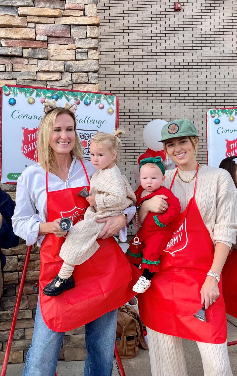 Korie Robertson, left, and her daughter Sadie Robertson Huff hold Sadie's daughters Honey, 2, left, and Haven, 6 months, while ringing bells with other family members for the Salvation Army's red kettle Christmas campaign in West Monroe on Dec. 9, 2023.