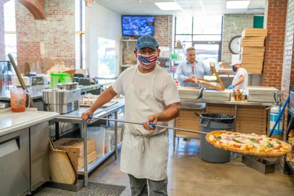 Joel Vargas of Aliño Pizzeria pulls a Margherita Pizza out of a wood-fired oven. It has fresh buffalo mozzarella, homemade San Marzano tomato sauce, fresh basil and fresh garlic.