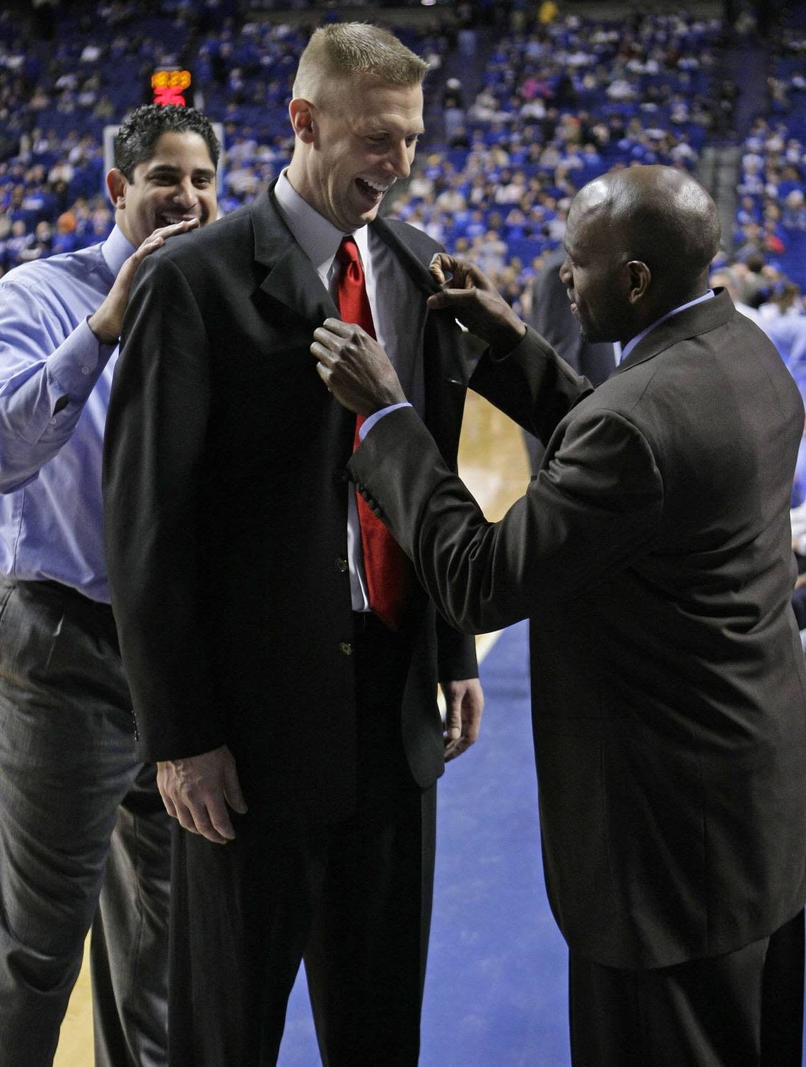 With former Kentucky assistant coach Orlando Antigua looking on, UK’s Tony Delk straightens the jacket of former teammate Mark Pope before the Wildcats played Georgia in Rupp Arena on Jan. 9, 2010.