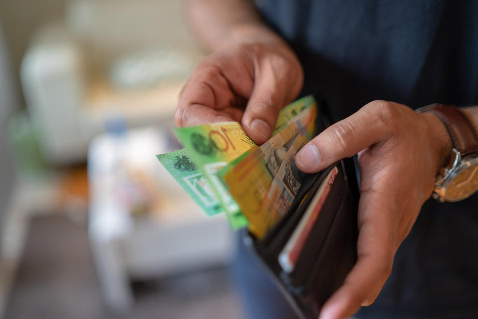 a male taking money out of the wallet.