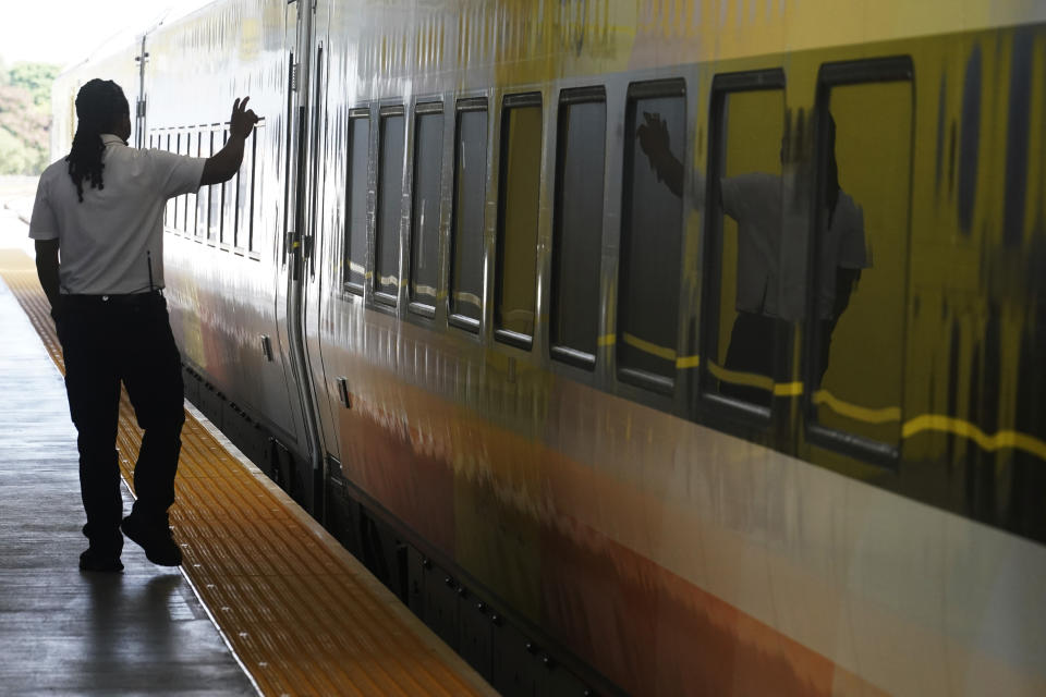 A Brightline employee waves to passengers as the train departs the Fort Lauderdale station, Sept. 8, 2023, in Fort Lauderdale, Fla. The first big test of whether privately owned high-speed passenger train service can prosper in the United States will launch Friday, Sept. 22, when Florida's Brightline begins running trains between Miami and Orlando. (AP Photo/Marta Lavandier)