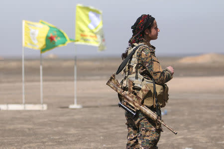 A Syrian Democratic Forces (SDF) female fighter stands with her weapon east of Raqqa city, Syria March 26, 2017. REUTERS/Rodi Said