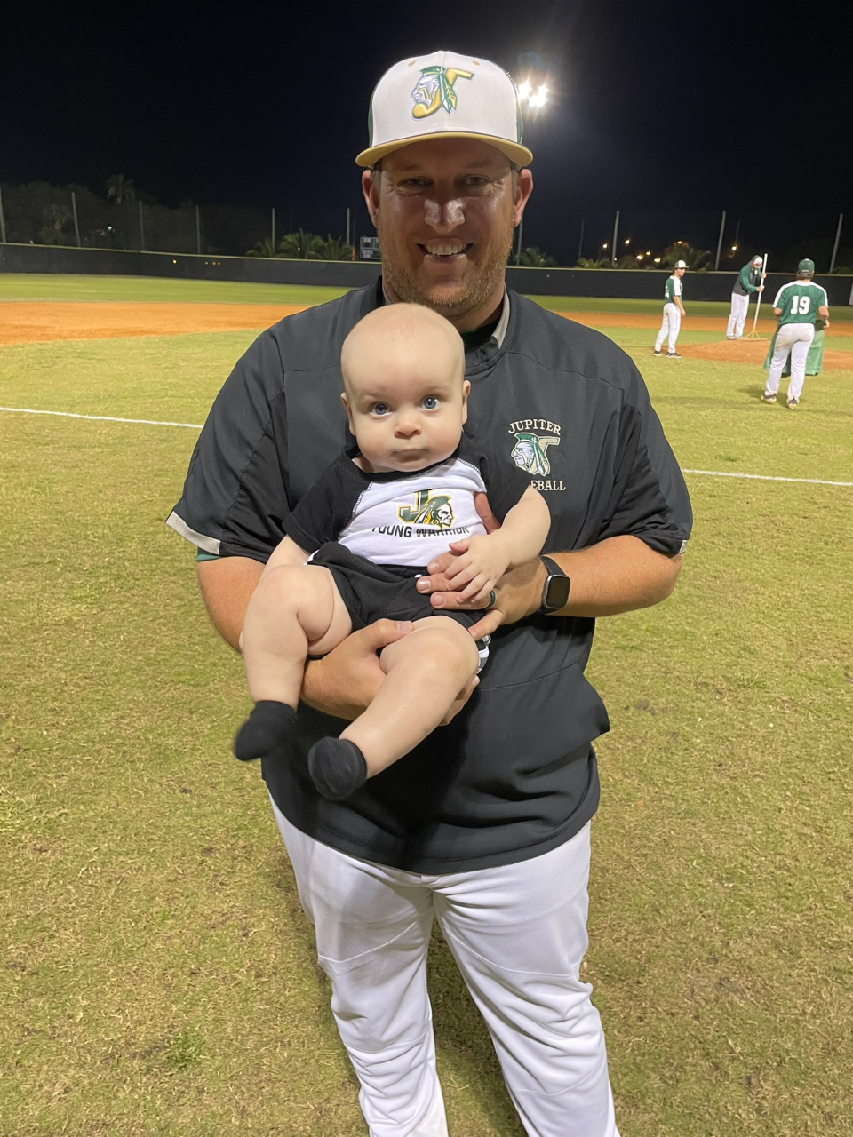 Assistant-turned-head coach Kyle Young pictured with his son, K.J., at his first-ever Jupiter High baseball game last March.