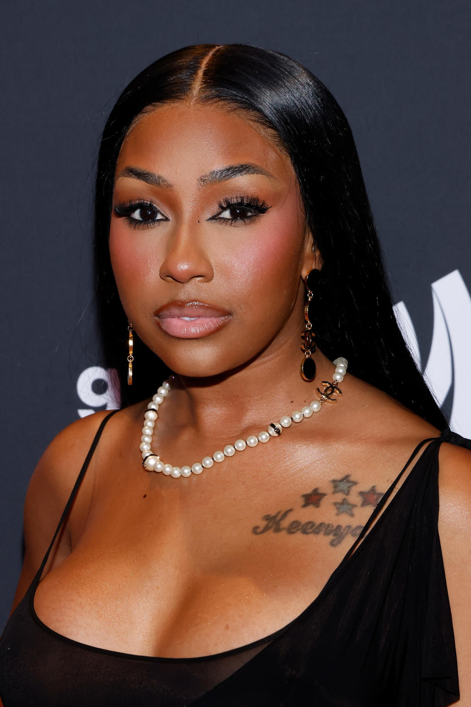 Justine Skye on the red carpet, wearing elegant jewelry and a stylish black dress, featuring a pearl necklace and earrings